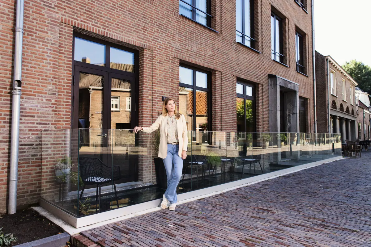 Vrouw poseert bij haar nieuwbouwwoning.
