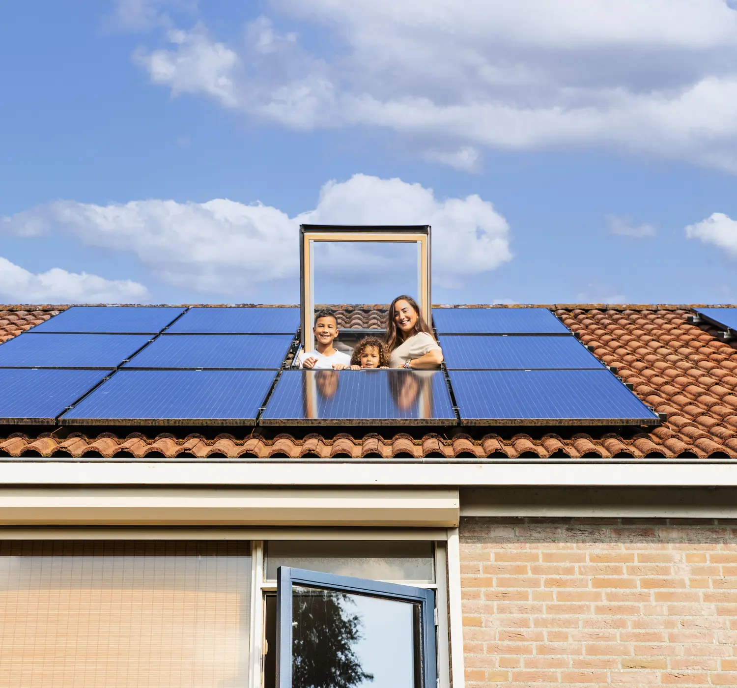 Gezin kijkt door het dakraam naar buiten. Op he dak liggen 10 zonnepanelen.