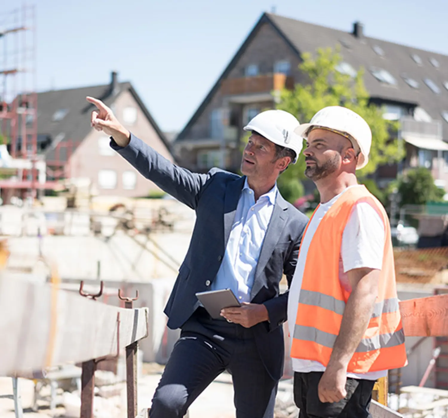 Opzichter en bouwvakker op de bouwplaats kijken omhoog.